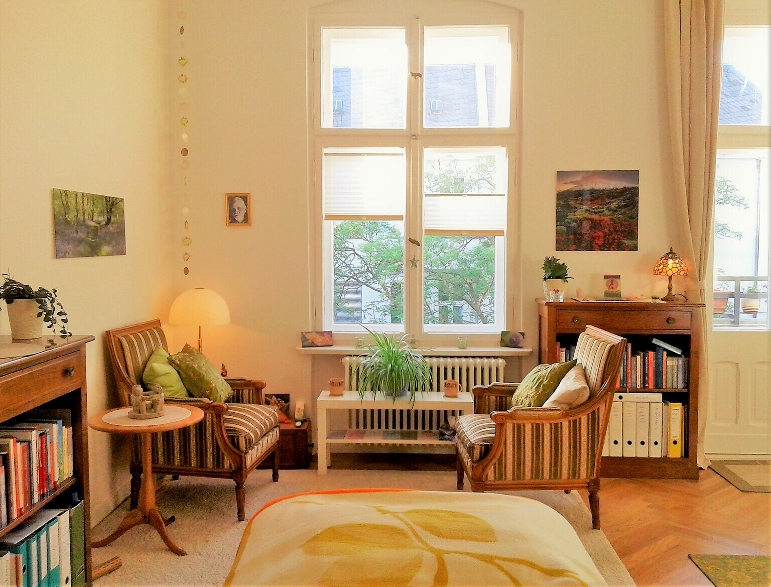 Heller Praxisraum von Uta Susanne Lowack mit zwei Sesseln, Bücherregal und grossem Fenster